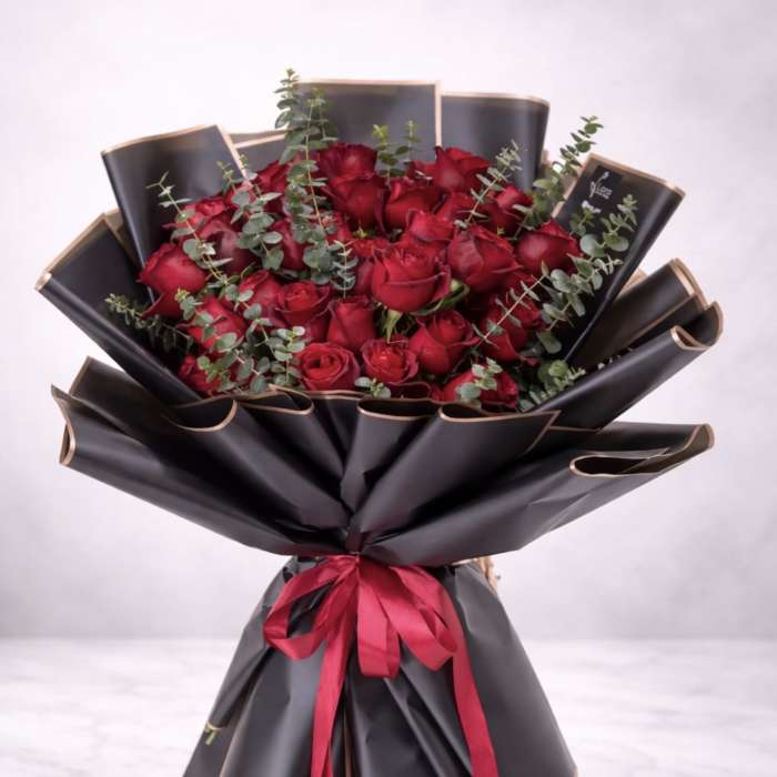 Bouquet of red roses wrapped in black paper with a red ribbon