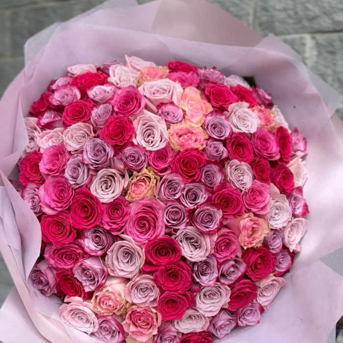 Large bouquet of pink and lavender roses wrapped in pale pink paper