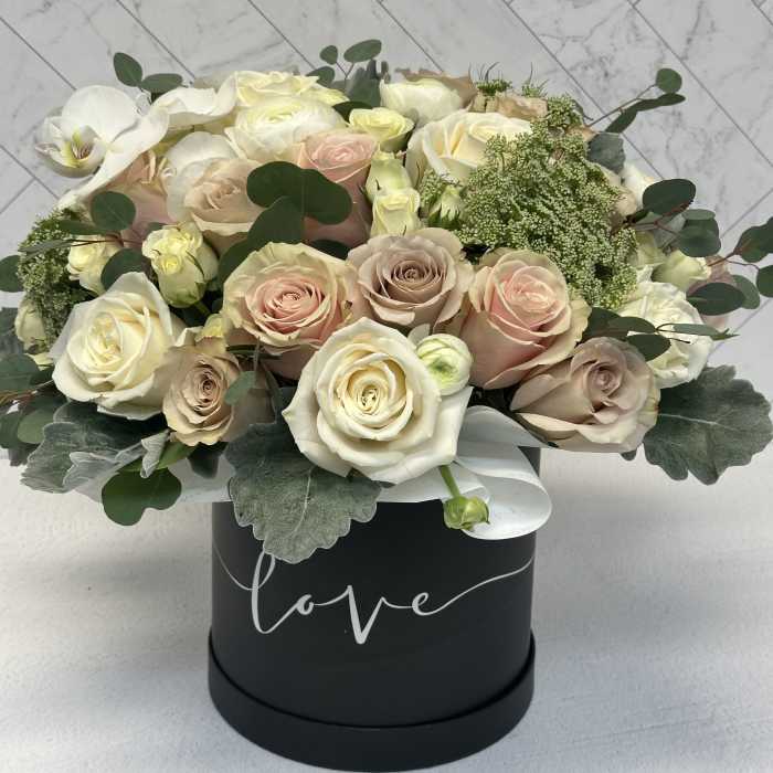 Bouquet of pale roses and white orchids in a black hat box