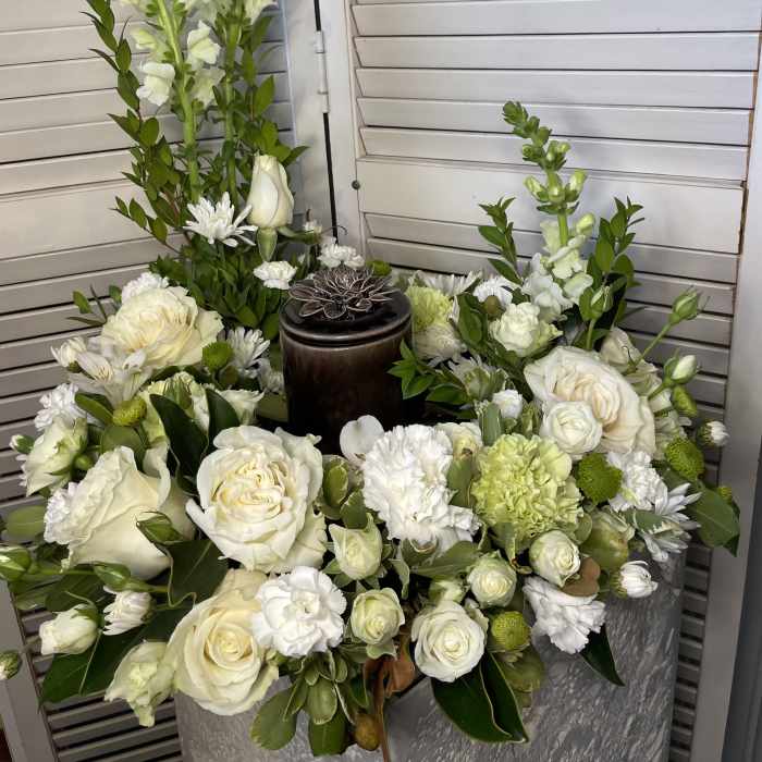 White floral arrangement with roses, snapdragons, and chrysanthemums in a silver container