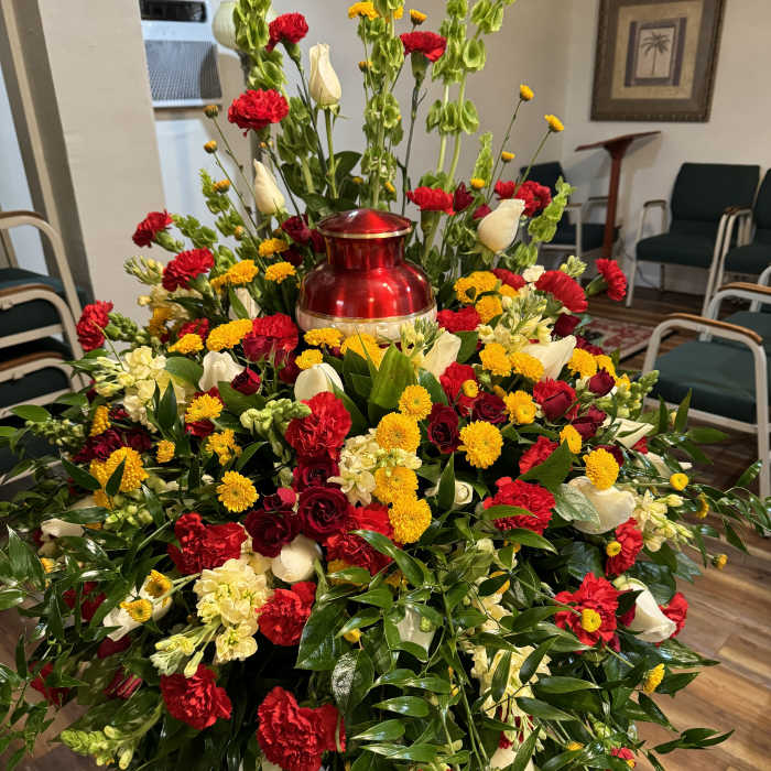 Large red, yellow, and white floral funeral spray with a red urn centerpiece