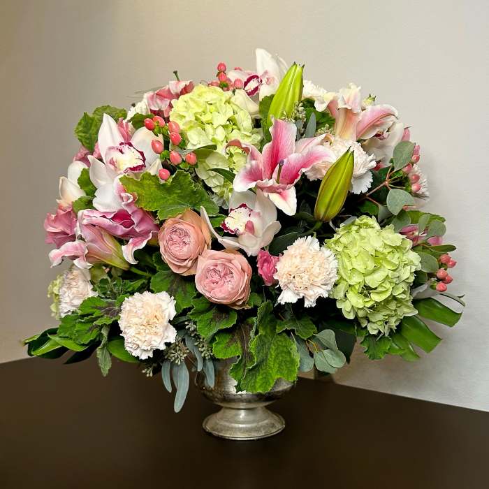 Mixed pink and white floral arrangement in a silver pedestal vase