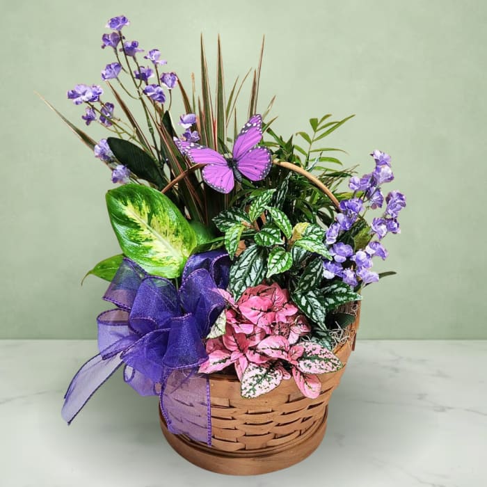 Basket arrangement with purple flowers, colorful foliage, and a purple ribbon bow