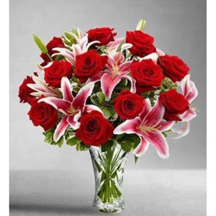 Arrangement of red roses and pink lilies in a clear glass vase