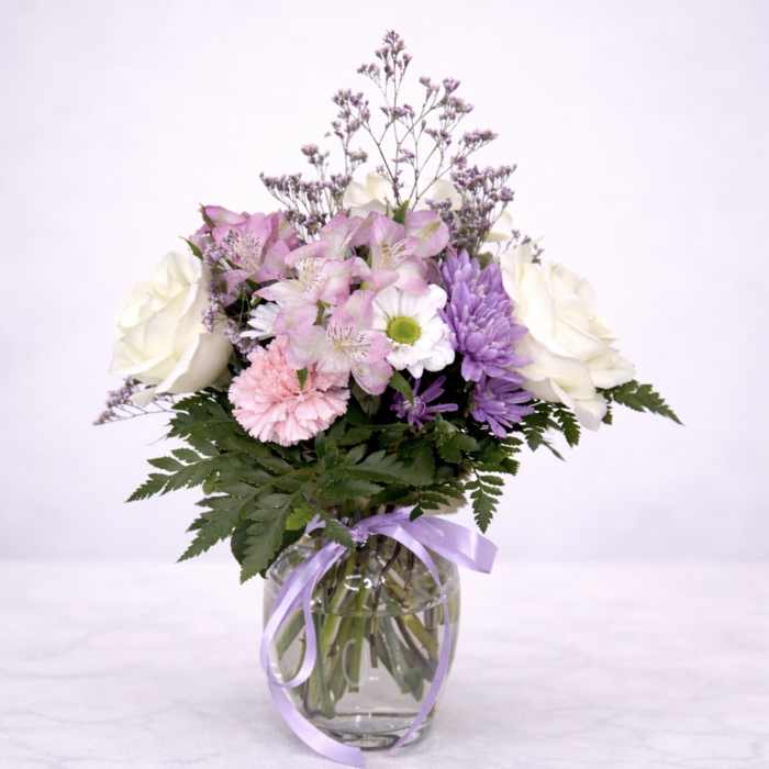 Pink and white mixed bouquet in a glass vase with a lavender ribbon
