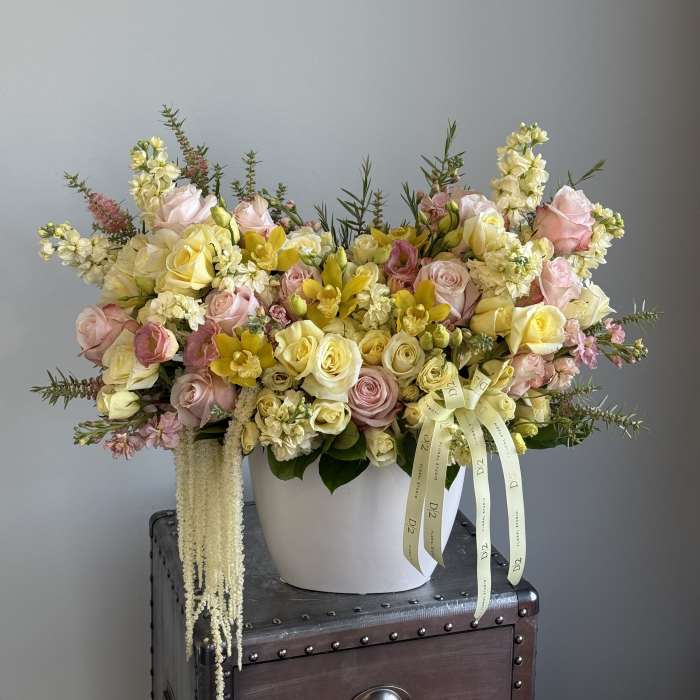 Large pastel flower arrangement in a white vase with pink and yellow blooms