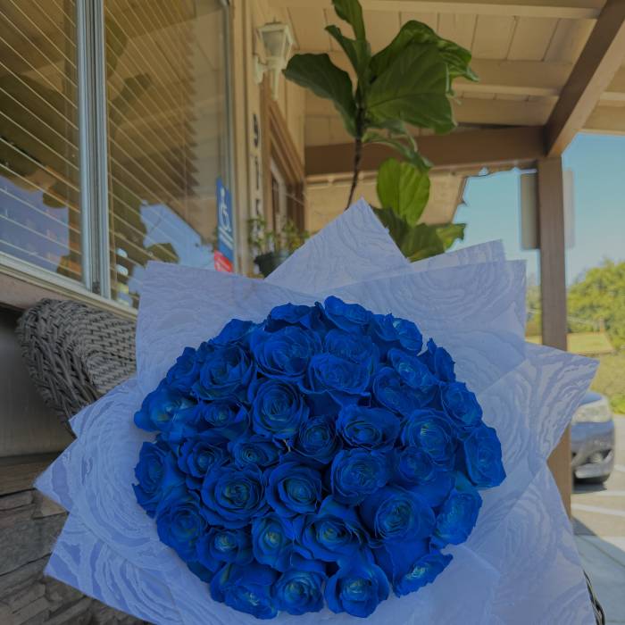 Bouquet of vivid blue roses wrapped in white paper