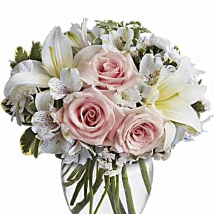 Pink roses and white lilies arranged in a clear glass vase
