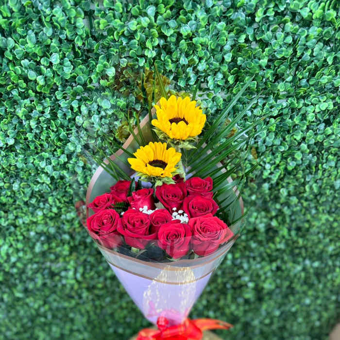 Bouquet of red roses and yellow sunflowers wrapped in clear film with a red bow