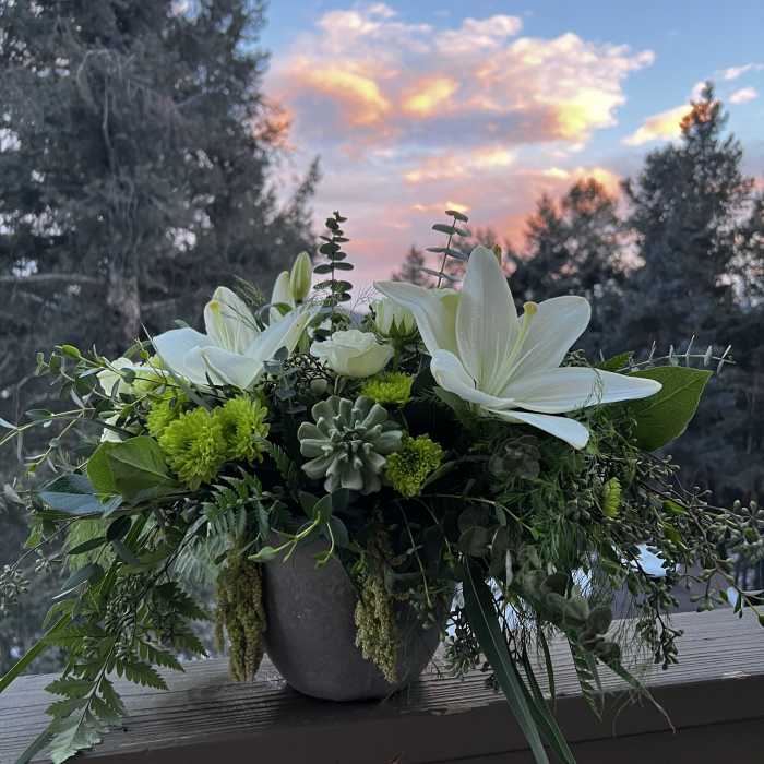 White lilies and green blooms in a gray vase