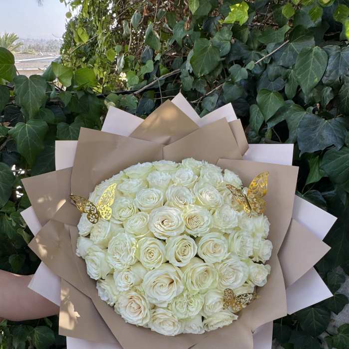 Bouquet of white roses wrapped in tan paper with gold butterfly accents