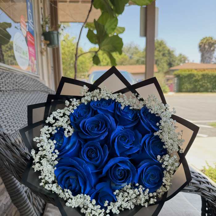 Bouquet of vivid blue roses with white baby's breath in black wrap