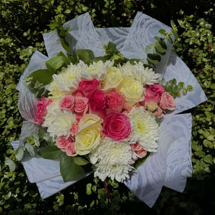 Bouquet of pink and white roses with white chrysanthemums wrapped in white paper