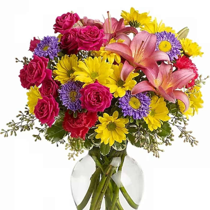 Bouquet of pink roses, lilies, and yellow daisies in a clear glass vase