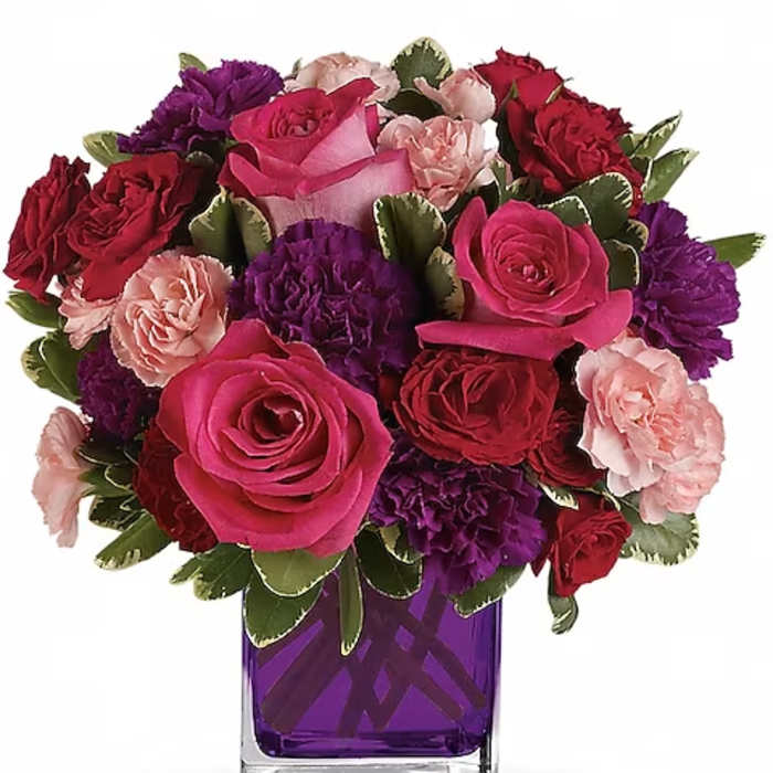 Bouquet of pink, red, and purple flowers in a purple glass vase