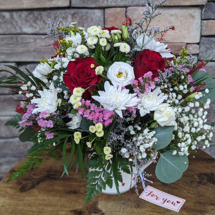 Mixed bouquet of red and white flowers in a white vase