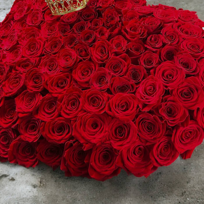 Heart-shaped arrangement of red roses with a gold crown on top
