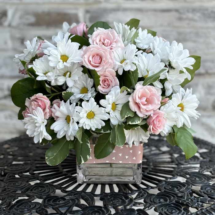 Pink roses and white daisies in a square glass vase