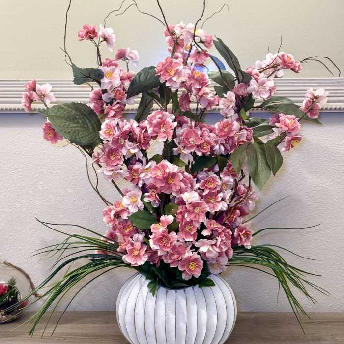 Pink blossoms arranged in a white ribbed vase with tall branches