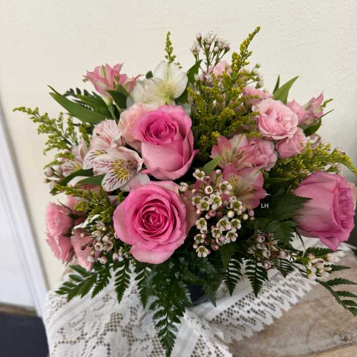 Pink roses and alstroemeria arranged in a vase with small white filler flowers