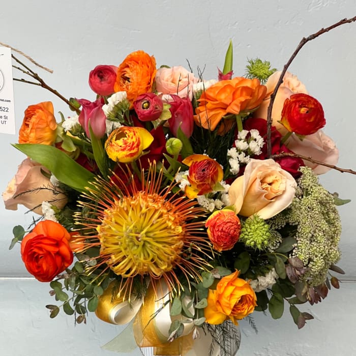 Bright mixed bouquet with orange, red, and peach flowers in a glass vase