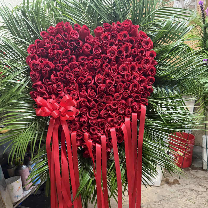 Heart-shaped red rose arrangement with long red ribbons