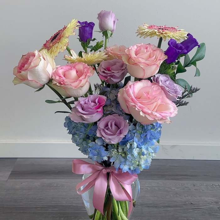 Pink and lavender roses with blue hydrangeas in a glass vase