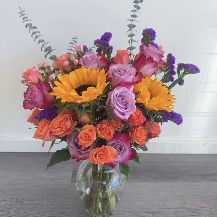 Mixed bouquet of roses and sunflowers in a clear glass vase
