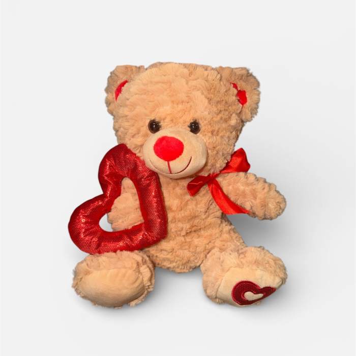 Teddy bear holding a red heart with a red ribbon