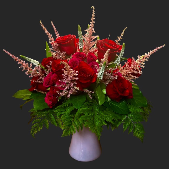 Red roses and pink filler flowers in a white vase
