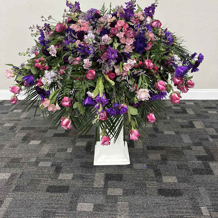 Large pink and purple floral spray on a white pedestal