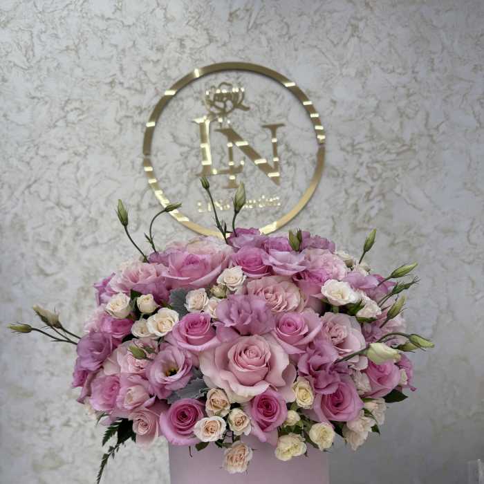 Pink and cream roses arranged in a round pink box
