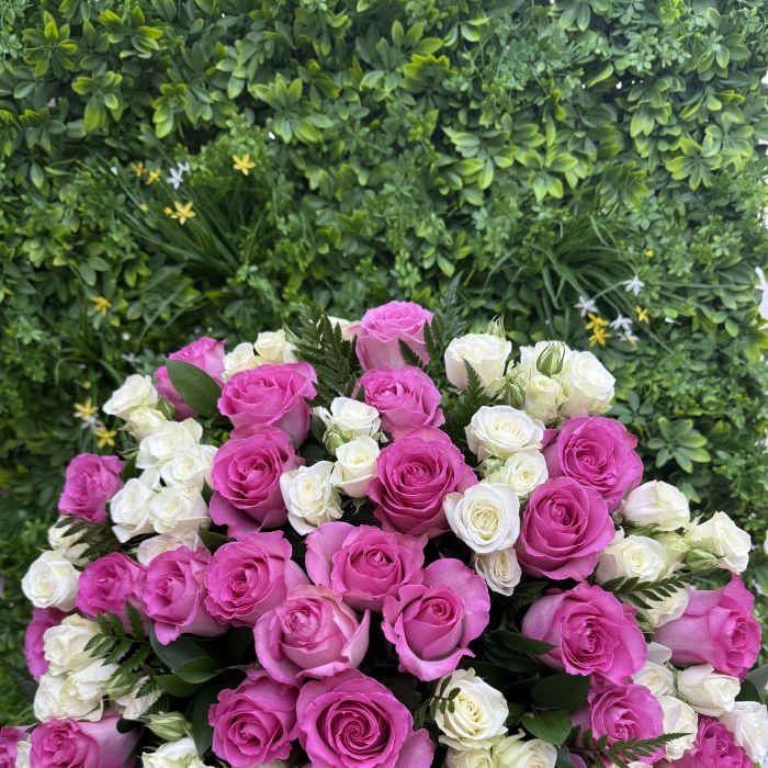 Bouquet of pink and white roses against a green floral wall