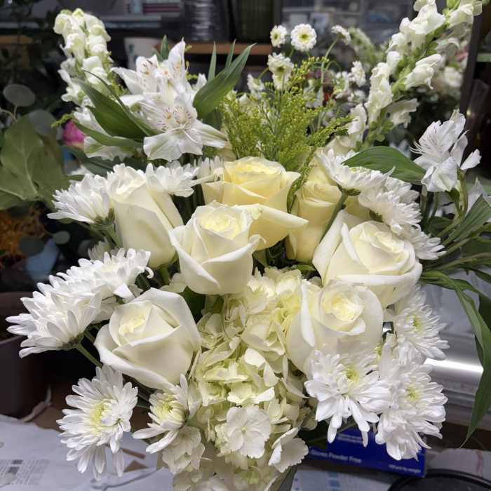 White roses and daisies arranged in a vase with pale hydrangea