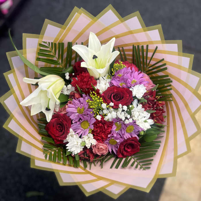 Bouquet of red, pink, and white flowers with lilies and roses