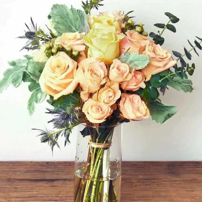 Peach and pale yellow roses in a clear glass vase