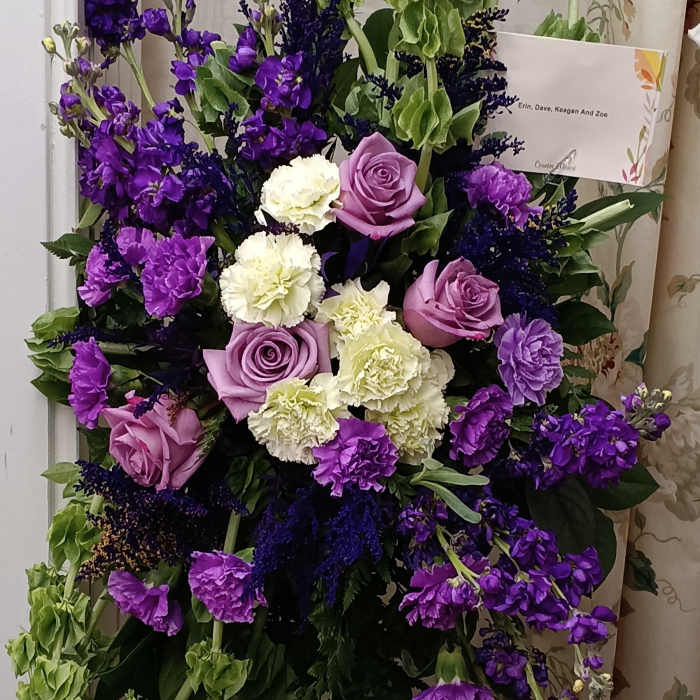 Purple and white floral standing spray with cascading green blooms