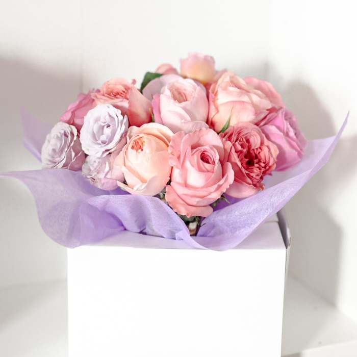 Pink and lavender rose bouquet wrapped in purple tissue paper