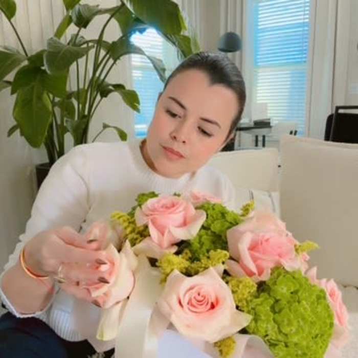Woman holding a bouquet of pink roses and green hydrangeas in a white box