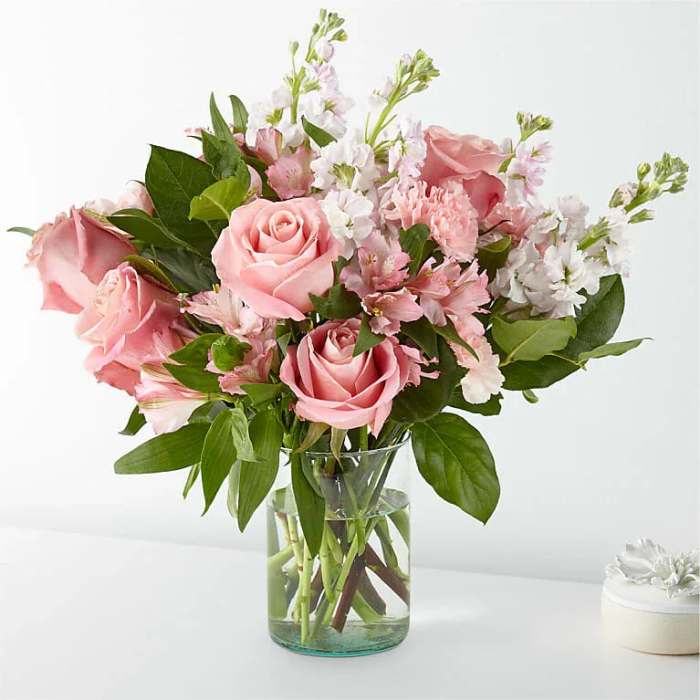 Pink roses and white flowers arranged in a clear glass vase