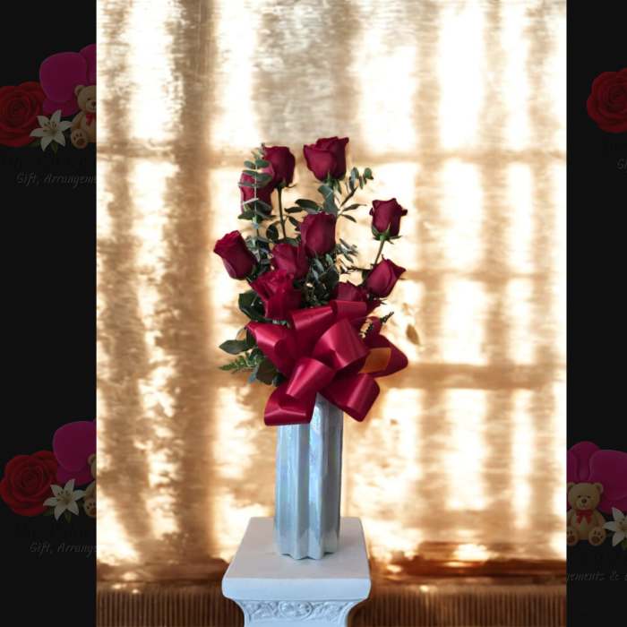 Tall bouquet of red roses in a silver vase with a large red ribbon