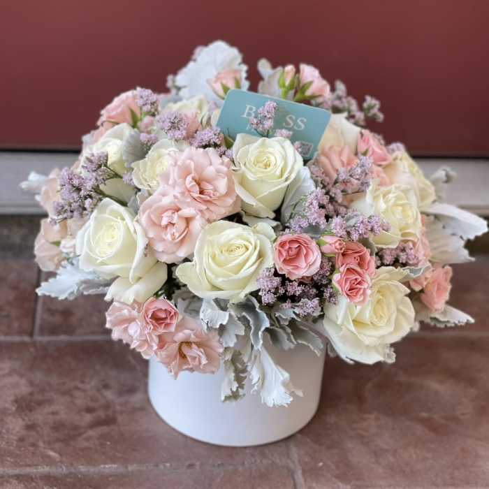 Pink and white roses arranged in a white box
