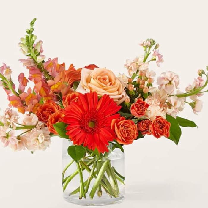 Orange and peach flowers in a clear glass vase