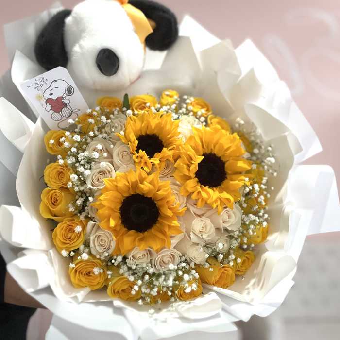 Bouquet of yellow sunflowers and pale roses with a plush panda topper