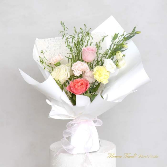 Bouquet of pastel roses and carnations wrapped in white paper
