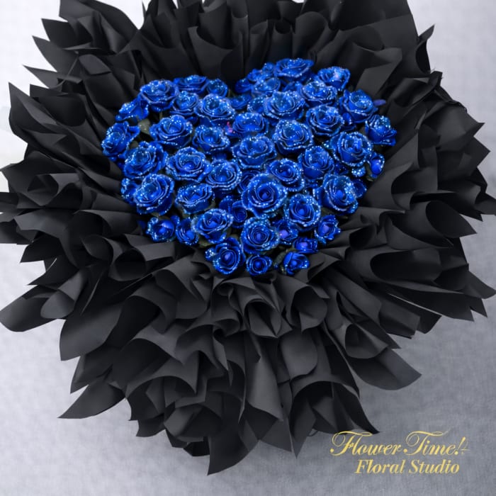 Heart-shaped bouquet of blue roses wrapped in black paper