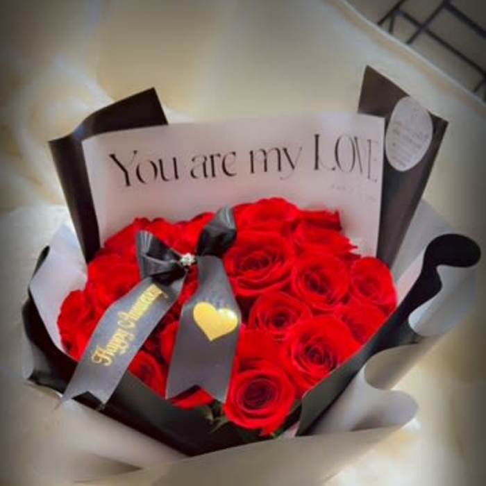 Bouquet of red roses wrapped in black and white paper with a love note