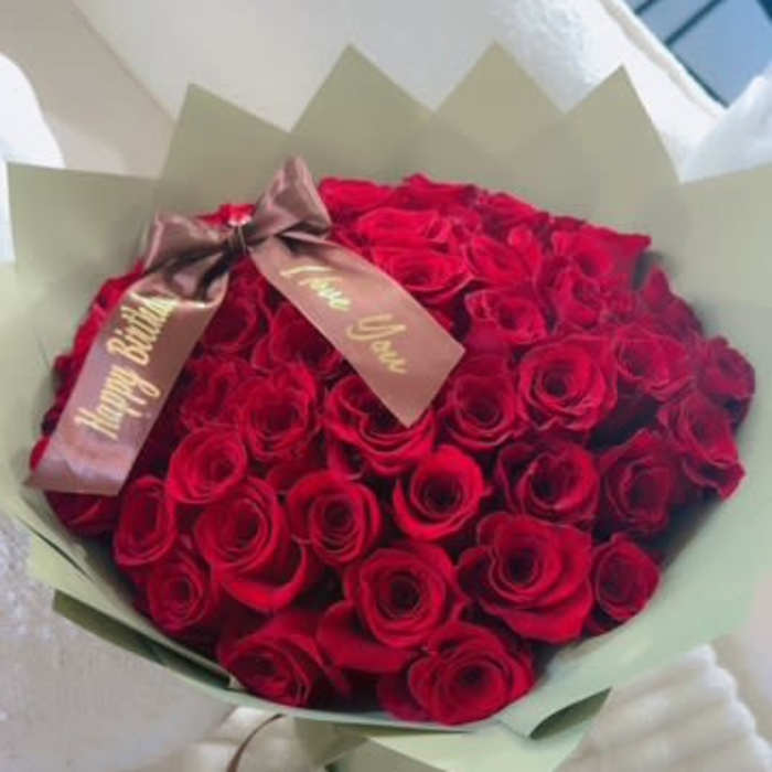 Bouquet of red roses wrapped in pale green paper with a ribbon