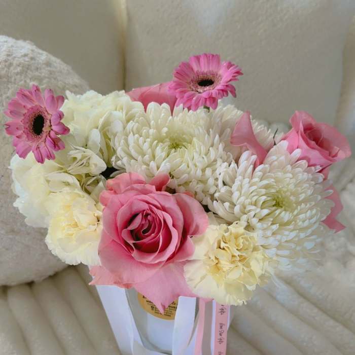 Pink and white bouquet with roses, chrysanthemums, and gerbera daisies in a white container
