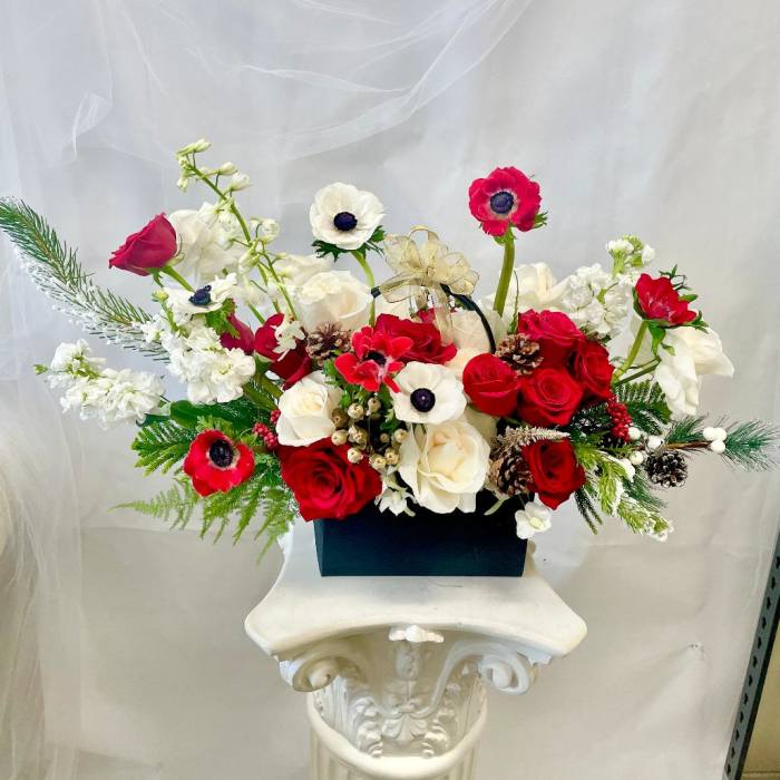 Red and white floral arrangement in a black box with a gold ribbon